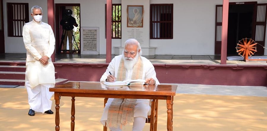 PM Modi writes in the visitors' diary at Sabarmati Ashram. Credit: Gujarat Information Department