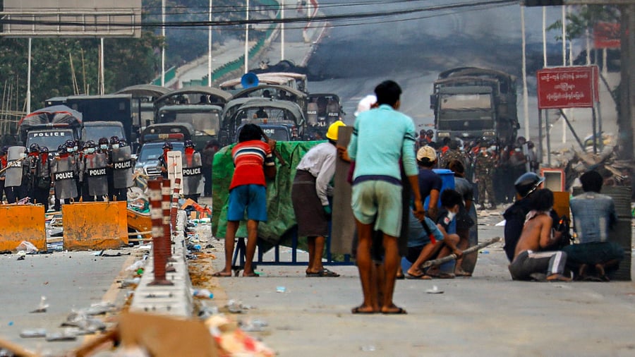 Protesters take cover behind homemade shields as they confront the police during a crackdown on demonstrations against the military coup in Hlaing Tharyar township in Yangon. Credit: AFP Photo