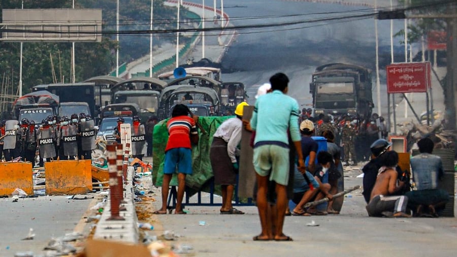 Protesters take cover behind homemade shields as they confront the police during a crackdown on demonstrations against the military coup in Hlaing Tharyar township in Yangon. Credit: AFP.