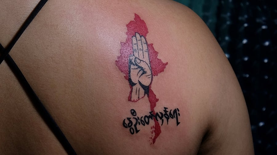 A woman displays a tattoo with a three-finger salute and the phrase 'spring revolution' over a map of Myanmar after it was finished in a tattoo shop in Yangon. Credit: Reuters Photo