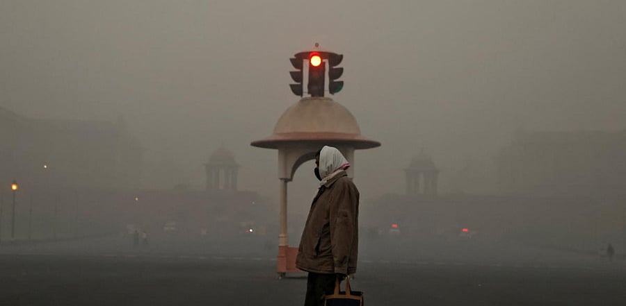 An office-goer walks past a traffic signal near various government ministries on a smoggy morning in New Delhi. Credit: Reuters Photo 