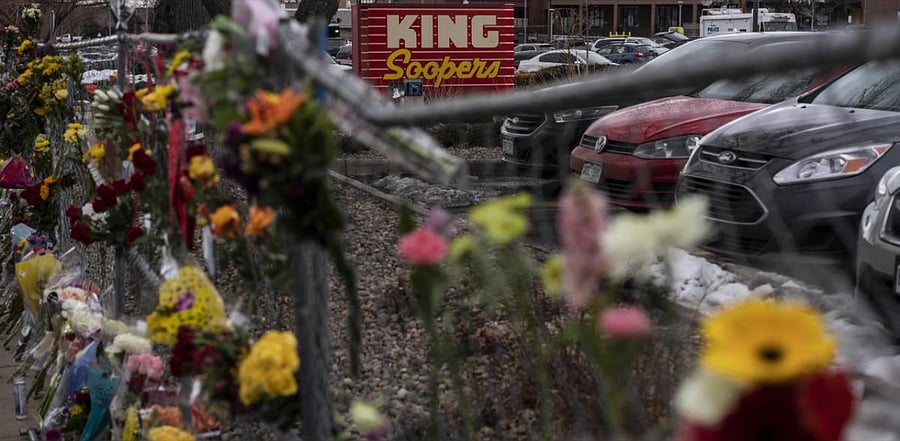 Memorials and flowers are left on the fencing surrounding the grocery store the day after a gunman opened fired at a King Sooper's grocery store. Credit: AFP photo.