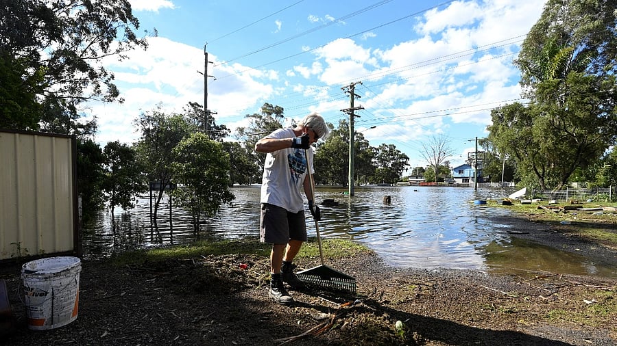 A man cleans up debris in front of his house as the state of New South Wales experiences widespread flooding. Credit: Reuters
