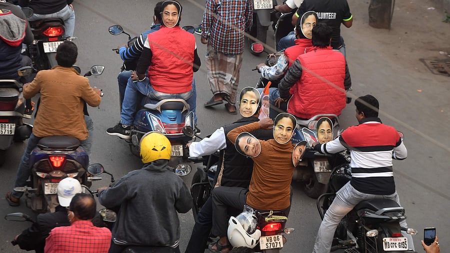 Trinamool Congress (TMC) party workers on their motorbikes wearing face cut-outs of West Bengal state Chief Minister Mamata Banerjee. Credit: AFP Photo