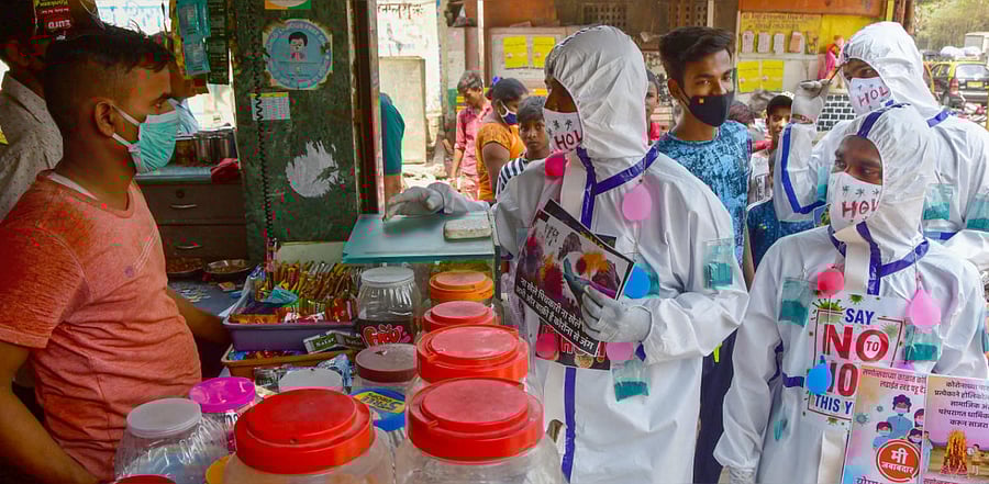 Social workers from Sion, wearing PPE suits, distribute pamphlets among residents of Dharavi slums during an awareness campaign on not to celebrate Holi this year, amid coronavirus pandemic, in Mumbai. Credit: PTI photo.