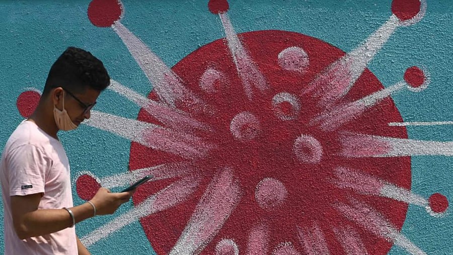 A pedestrian walks past a wall mural depicting the Covid-19 coronavirus, in Mumbai on March 29, 2021. Credit: AFP Photo