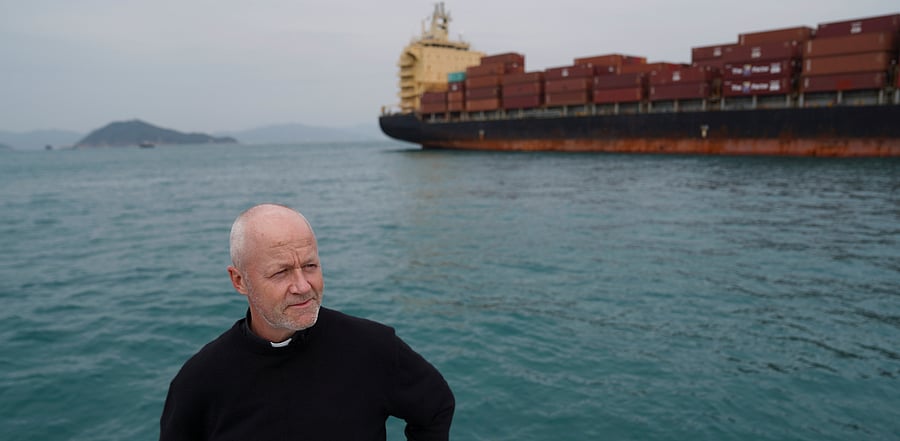 Reverend Stephen Miller of the Mission to Seafarers poses for a picture on a boat near a container ship during a trip to deliver supplies to sailors stranded on visiting cargo vessels due to Covid-19. Credit: Reuters Photo