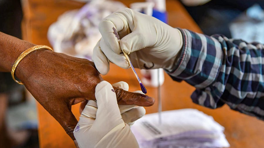  A polling official marks the finger of a voter during the first phase of Assam Assembly Elections, at a polling station in Samaguri, Saturday, March 27, 2021. Credit: PTI Photo