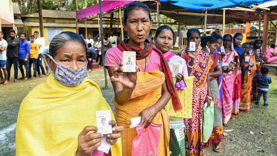 Tribal women wait to cast their votes during the second phase of Assam Assembly polls, in Morigaon. Credit: PTI Photo