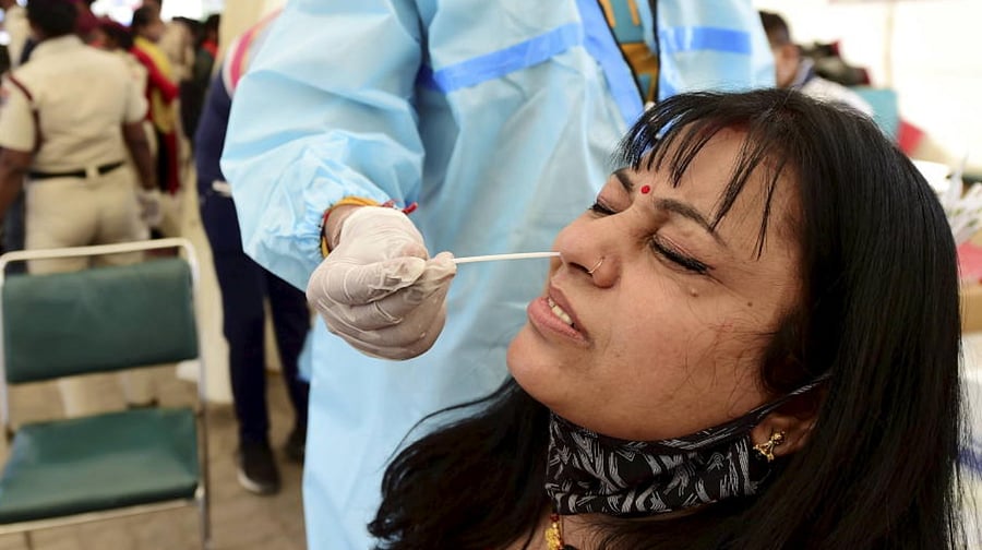 A health worker collects a nasal sample from a passenger for COVID-19 test, amid coronavirus pandemic, in New Delhi, Friday, April 2, 2021. Credit: PTI Photo