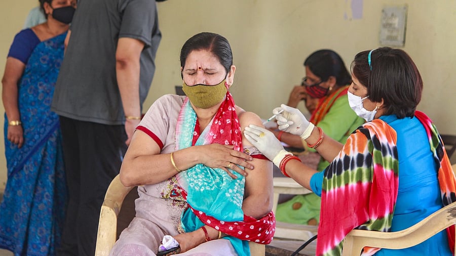 A medic administers the Covid-19 vaccine dose to a woman during a vaccination drive at a community centre, in Gurugram. Credit: PTI