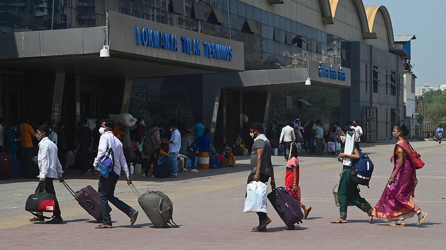 Passengers walk with their luggage outside Lokmanya Tilak Terminus railway complex to catch a train amidst rising Covid-19 coronavirus cases Mumbai. Credit: AFP File Photo