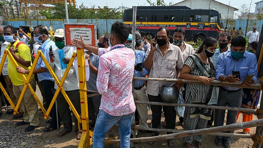 People stand behind a barrier outside a Covid-19 coronavirus vaccination centre as vaccination stopped due to shortage of vaccine supplies, in Mumbai on April 9, 2021. Credit: AFP Photo