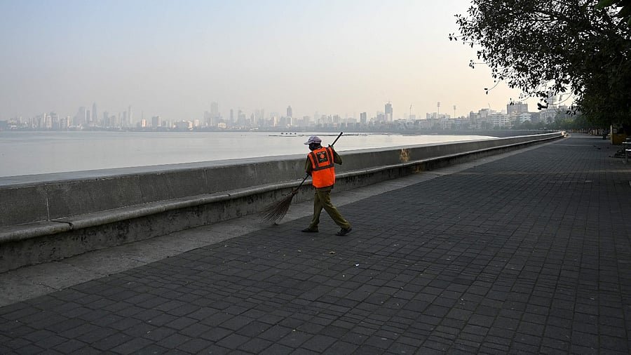 A civil authority worker cleans a deserted area near the sea front during restrictions imposed by the state government amidst rising Covid-19 coronavirus cases, in Mumbai on April 15, 2021. Credit: AFP Photo