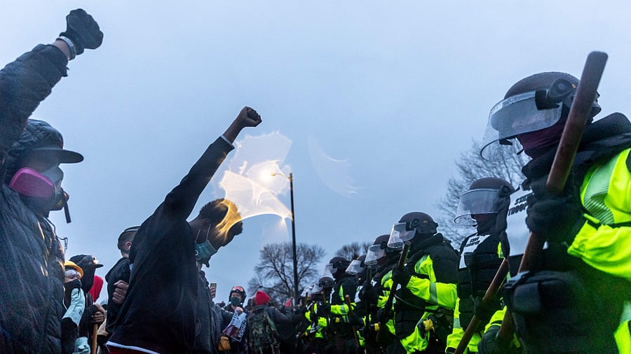 In this file photo people raise their fists, facing a line of State Troopers at the start of curfew to protest the death of Daunte Wright who was shot and killed by a police officer in Brooklyn Center, Minnesota. Credit: AFP photo