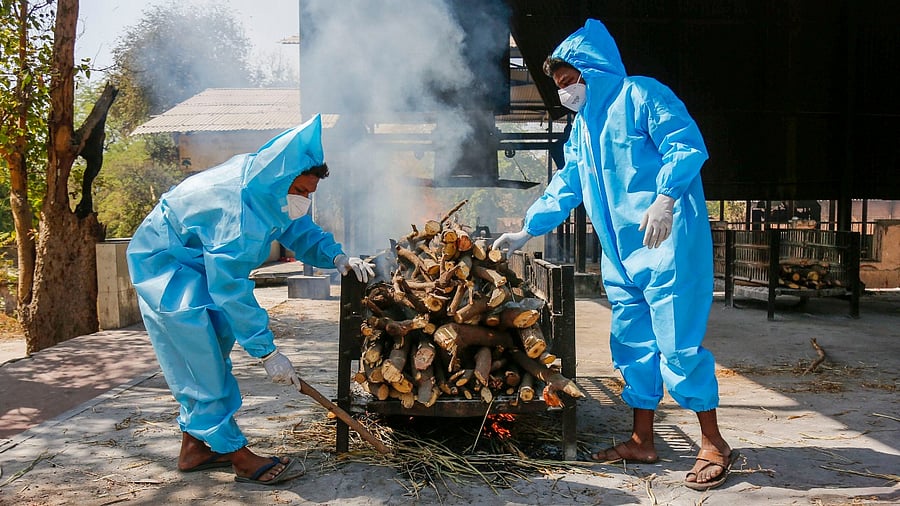 Frontline workers in personal protective equipment (PPE), arrange a funeral pyre for Covid-19 victim at a crematorium, in Ahmedabad. Credit: PTI Photo