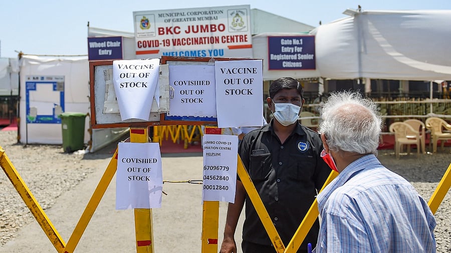 People stand behind a barrier outside a Covid-19 coronavirus vaccination centre after vaccination stopped due to shortage of supplies, in Mumbai, Tuesday, April 20, 2021. Credit: PTI Photo