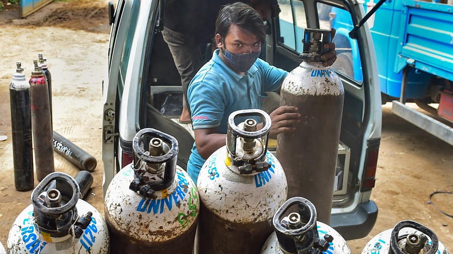 Workers sort medical oxygen cylinders meant for Covid-19 patients, before dispatching them to hospitals, amid surge in coronavirus cases, at BMTC bus stand in Bengaluru. Credit: PTI photo.