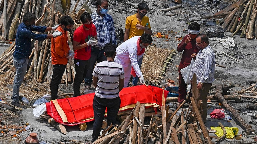 Family members and relatives perform the last rites amid the funeral pyres of victims who died of the Covid-19 coronavirus during mass cremation held at a crematorium in New Delhi. Credit: AFP photo