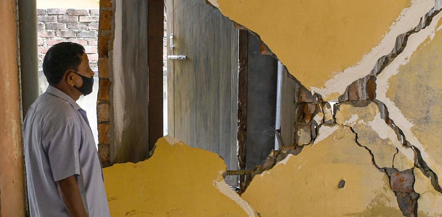 A man stands near a severely damaged wall due to a high-intensity earthquake, in Guwahati, Wednesday, April 28, 2021. Credit: PTI Photo