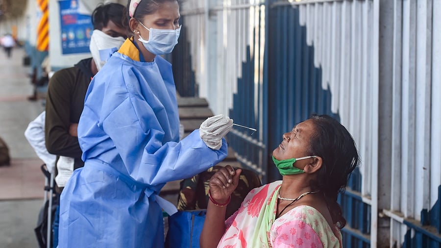 A BMC health worker takes swab sample for Covid-19 testing from passengers arriving from outstation, amid the ongoing second wave of coronavirus pandemic, at Dadar Railway Station in Mumbai. Credit: PTI photo