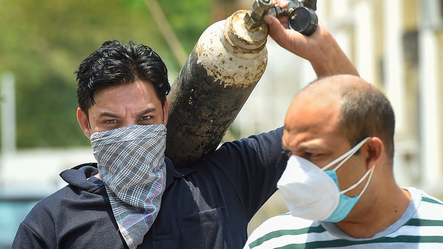 A relative carries an oxygen cylinder from a Gurudwara in Greater Kailash, that was offering free refilling of oxygen for COVID-19 patients amidst surge in coronovirus cases, in New Delhi. Credit: PTI File Photo