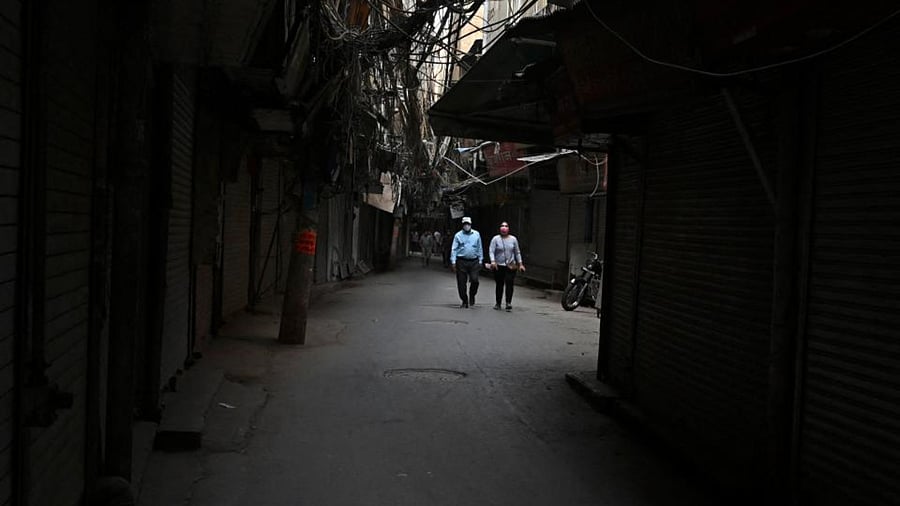 People walk along a deserted street past closed shops in the old quarters of New Delhi on May 5, 2021 as India's capital continues a lockdown imposed to curb the spread of the amid Covid-19 coronavirus.  Credit: AFP Photo