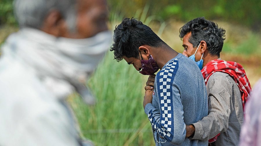 In this picture taken on May 5, 2021, the son (C) of a science school teacher, who died of the Covid-19 coronavirus grieves after lighting his father's funeral pyre at a crematorium in Moradabad. Credit: AFP Photo