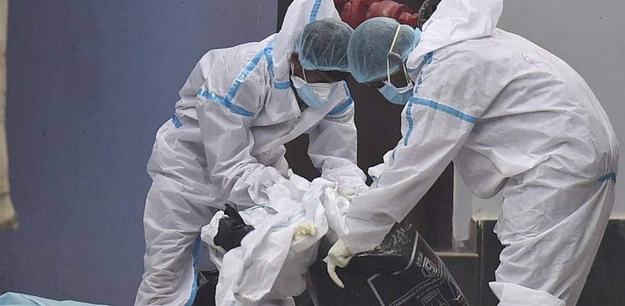 Workers wearing PPE suit pack Covid-19 waste to load on a vehicle for disposed at a state government run Covid hospital in Kolkata, Tuesday, May 11, 2021. Credit: PTI Photo