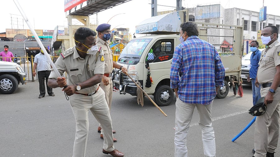 A policeman uses a lathi to enforce lockdown norms in Bijapur. Credit: DH Photo