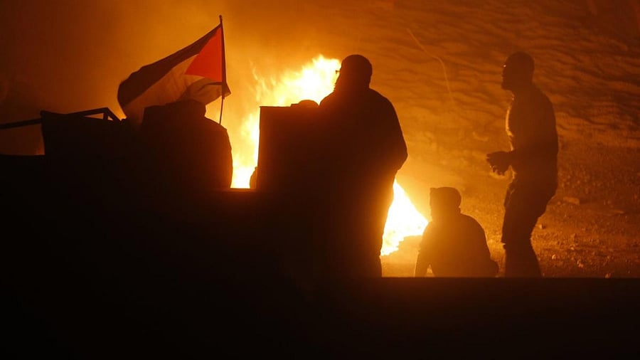 Palestinians stand near a flag of Palestine during an anti-Israel demonstration over tensions in Jerusalem. Credit: AFP Photo