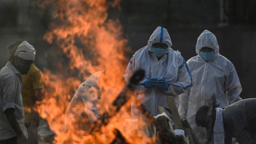 Relatives wearing Personal Protective Equipment (PPE) perform rituals during the cremation of their loved one who died due to the Covid-19 coronavirus, at a crematorium in New Delhi. Credit: Reuters Photo