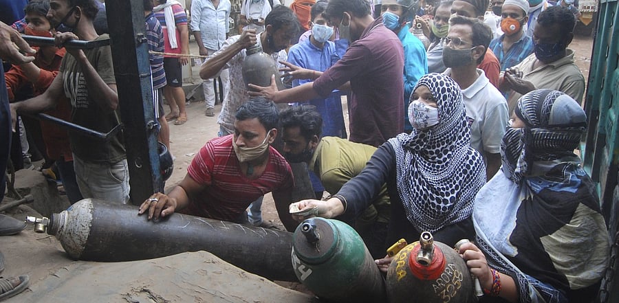 Family members of covid-19 patients crowd at an oxygen refilling centre. Credit: PTI Photo
