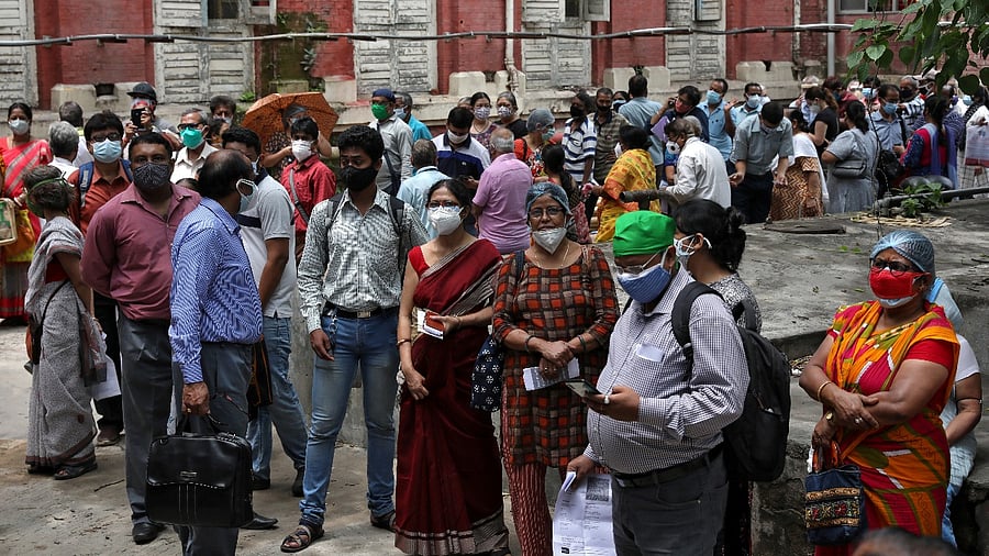People wearing protective face masks wait to receive their second dose of Covishield, a Covid-19 vaccine manufactured by Serum Institute of India, outside a vaccination centre in Kolkata. Credit: Reuters Photo