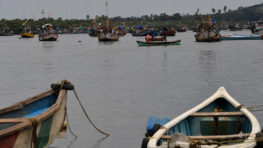 Boys row a boat near moored fishing boats at a fishing village off the city coast in the wake of the impending cyclone Tauktae in Mumbai. Credit: AFP Photo