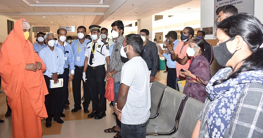 Shivarathri Deshikendra Swami of Suttur Mutt interacts with relatives of patients at JSS Medical College in Mysuru on Monday. DH Photo