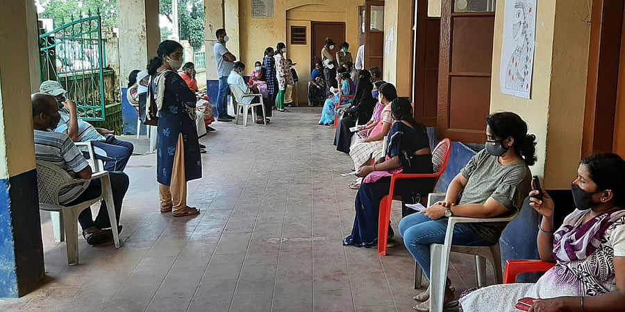 People wait for their turn to get vaccinated at the Covid-19 vaccination centre in Virajpet.