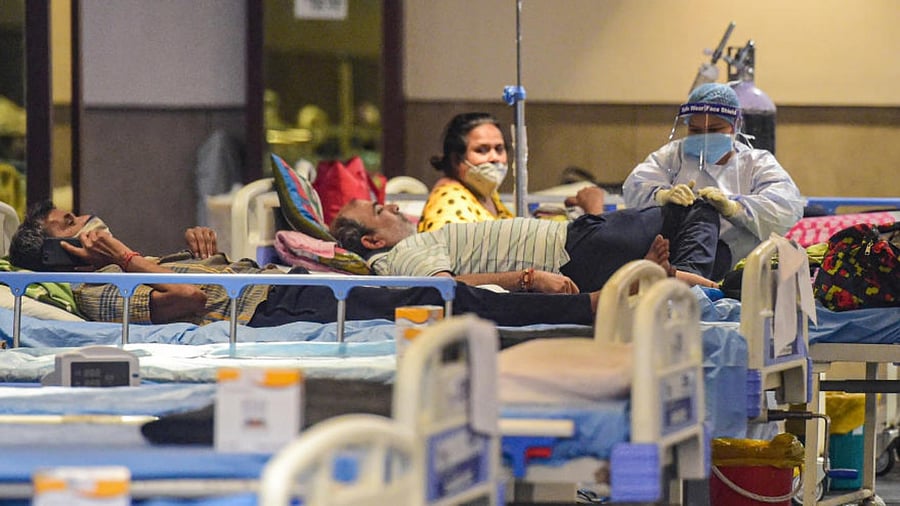 Health workers attend Covid-19 patients undergoing treatment at Shehnai Banquet Hall isolation centre, in New Delhi, Wednesday, May 19, 2021. Credit: PTI Photo