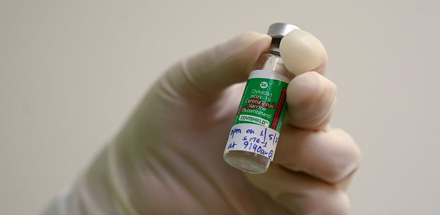 A medical worker holds a vial of Covishield. Credit: AFP Photo