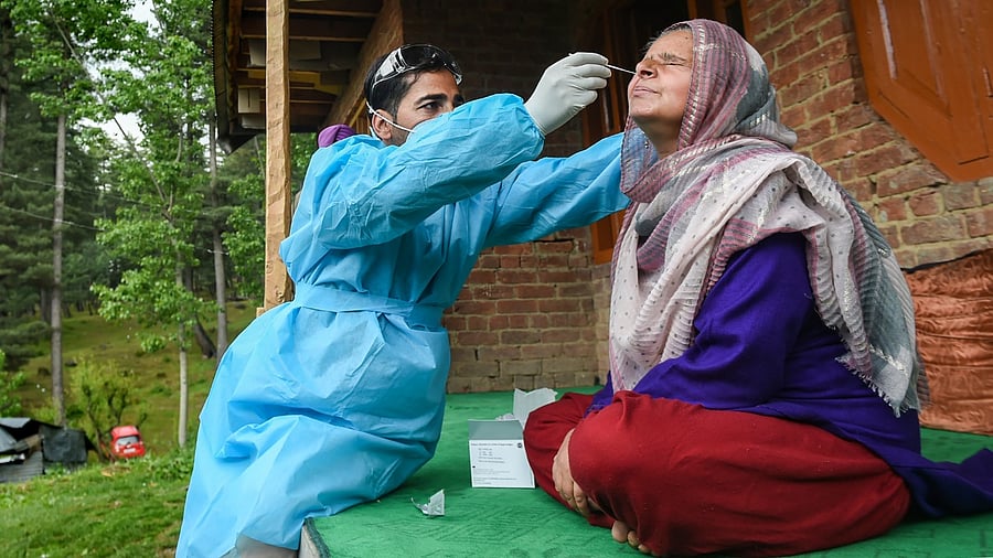 A health worker takes a swab sample of a woman for Covid-19 test during door to door testing campaign at Khag area in Budgam district of Kashmir, Thursday, May 20, 2021. Credit: PTI Photo
