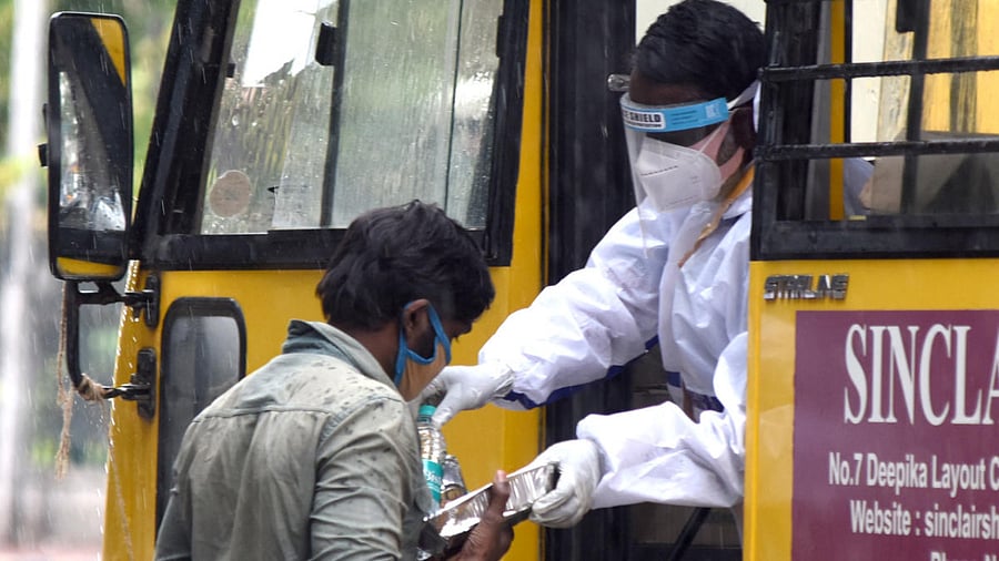 Those in need collect food from a volunteer during the Covid-19 lockdown at Hudson circle in Bengaluru. Credit: DH Photo/S K Dinesh