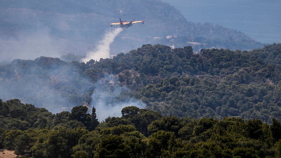 A fire fighting airplane sprays water to extinguish a wild fire on Mount Geraneia, west of Athens. Credit: AFP Photo