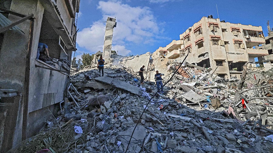 Palestinians look for salvageable items amid the rubbe of the six-storey Kuhail building which was destroyed in an early morning Israeli airstrike on Gaza City. Credit: AFP Photo