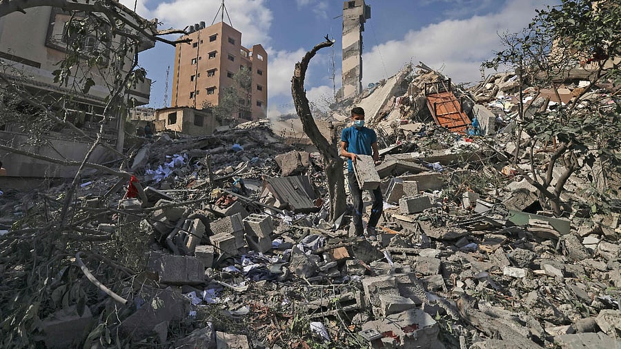 A Palestinian youth looks for salvageable items amid the rubbe of the Kuhail building which was destroyed in an early morning Israeli airstrike on Gaza City. Credit: AFP Photo