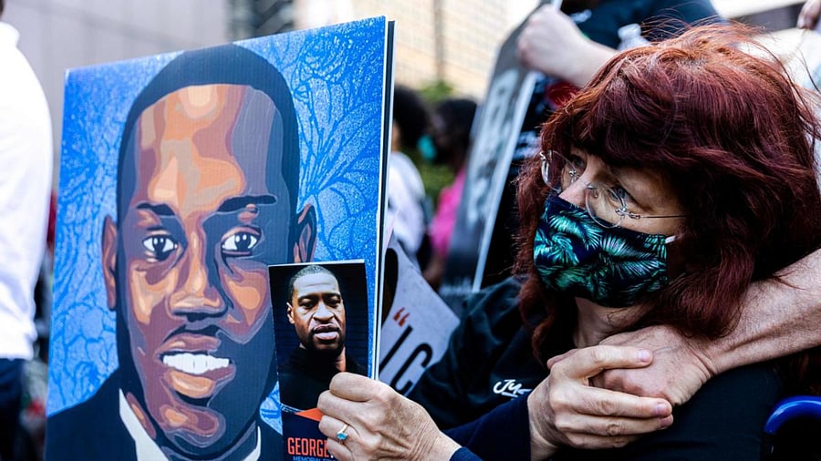 A woman holds portraits of Ahmaud Arbery and George Floyd during an event in remembrance of George Floyd in Minneapolis, Minnesota. Credit: AFP Photo