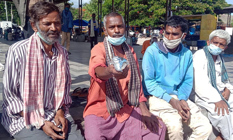 A shelterless person shows the food packet distributed at the Indira Canteen in Srirangapatna, Mandya district. Credit: DH Photo