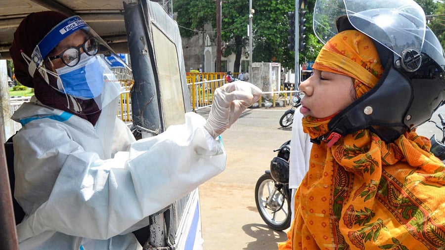 A medic collects swab sample of a woman for Covid-19 test during Covid-induced curfew in Bhopal, Tuesday, May 25, 2021. Credit: PTI Photo