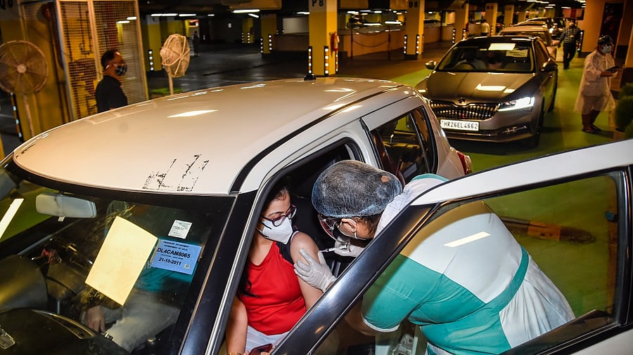 A health worker administers a dose of the Covid-19 vaccine to a woman, at a drive-through vaccination camp at Select City Walk mall, in New Delhi. Credit: PTI Photo