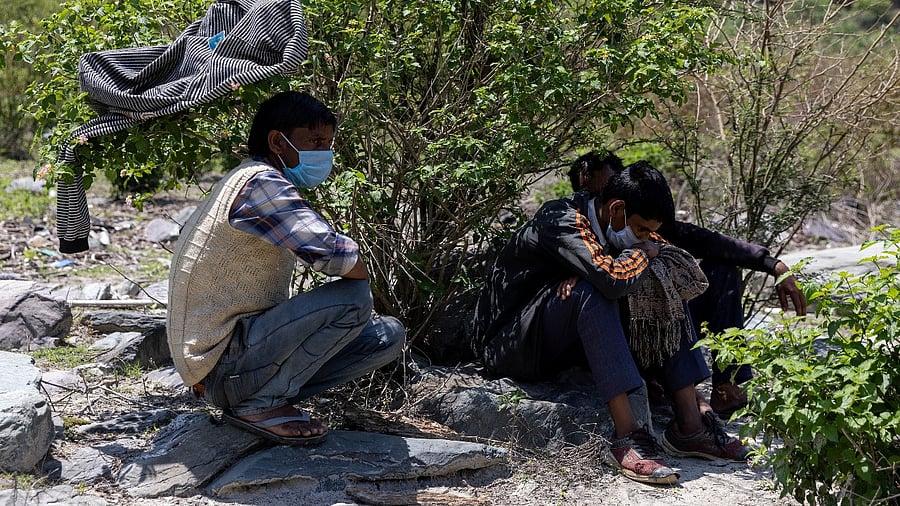 Suresh Kumar, 43, the husband of Pramila Devi, 36, who died from the coronavirus disease (Covid-19), and Devi's son Suraj Kumar, 16, watch her cremation on the banks of the river Ganges in Pauri Garhwal, in the northern state of Uttarakhand. Credit: Reuters photo
