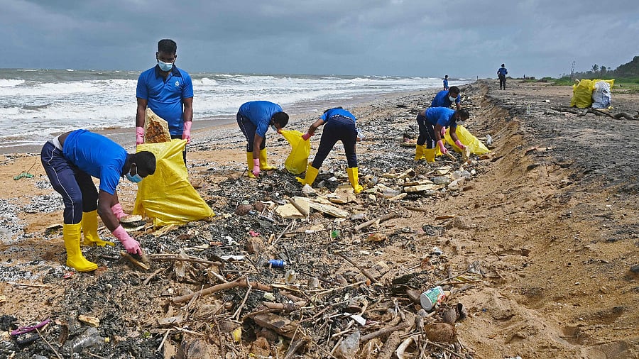 Sri Lankan Navy soldiers work to remove debris washed ashore from the Singapore-registered container ship MV X-Press Pearl, which has been burning for the eighth consecutive day in the sea off Sri Lanka's Colombo Harbour. Credit: AFP Photo